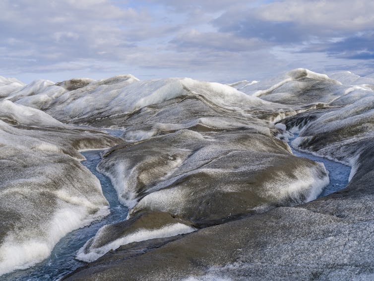 Dark snow with streams running through it.
