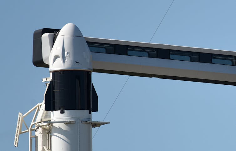 The top of a rocket with a conical capsule mounted on its tip.
